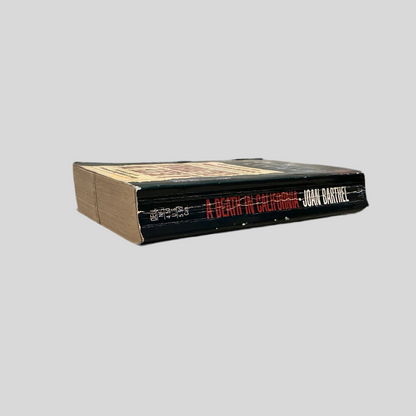 Side view of 'A Death in California' by Joan Barthel, showing the book’s black spine with the title and author's name in white and red text, with visible wear along the edges.